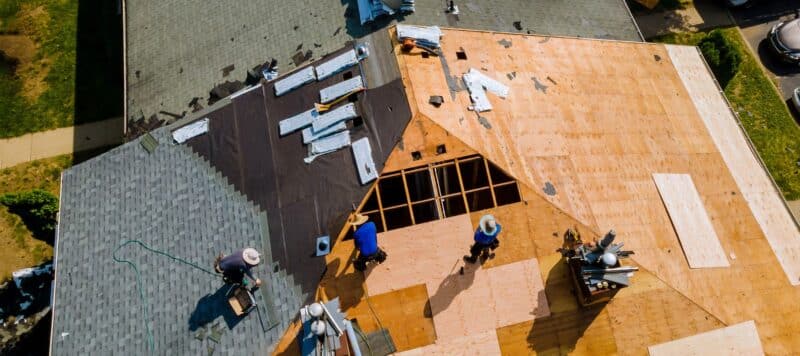 An aerial view of workers installing new roofing materials on a residential house